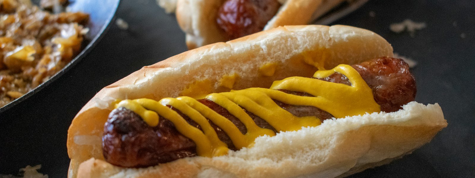 Hot dog topped with yellow mustard in a soft bun