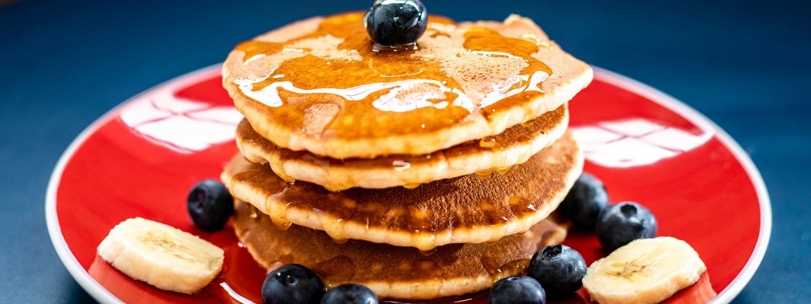 Stack of fluffy pancakes with syrup and berries