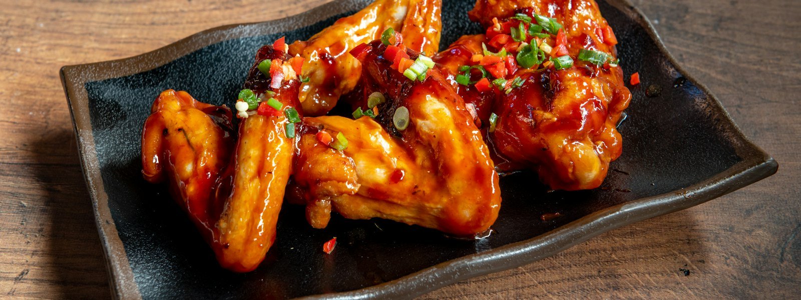 Saucy buffalo-style chicken wings on a black plate