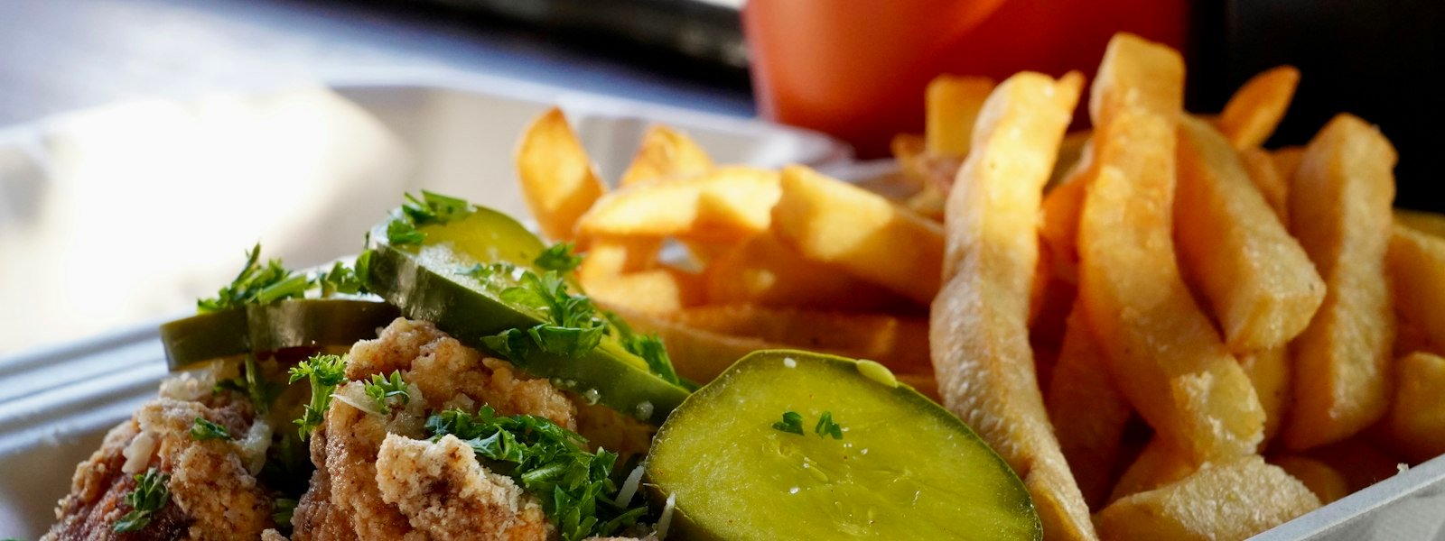 Fried chicken fingers with crinkle fries in a takeout box
