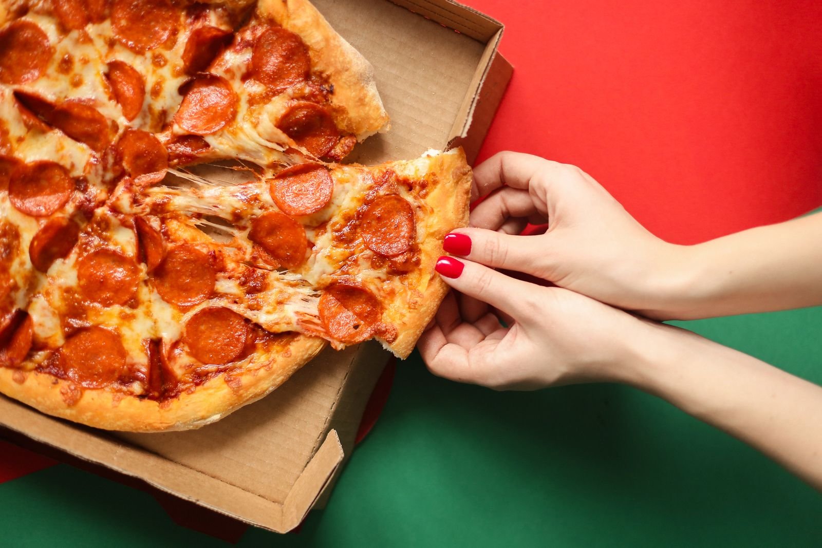 Pepperoni pizza slice being pulled from a delivery box