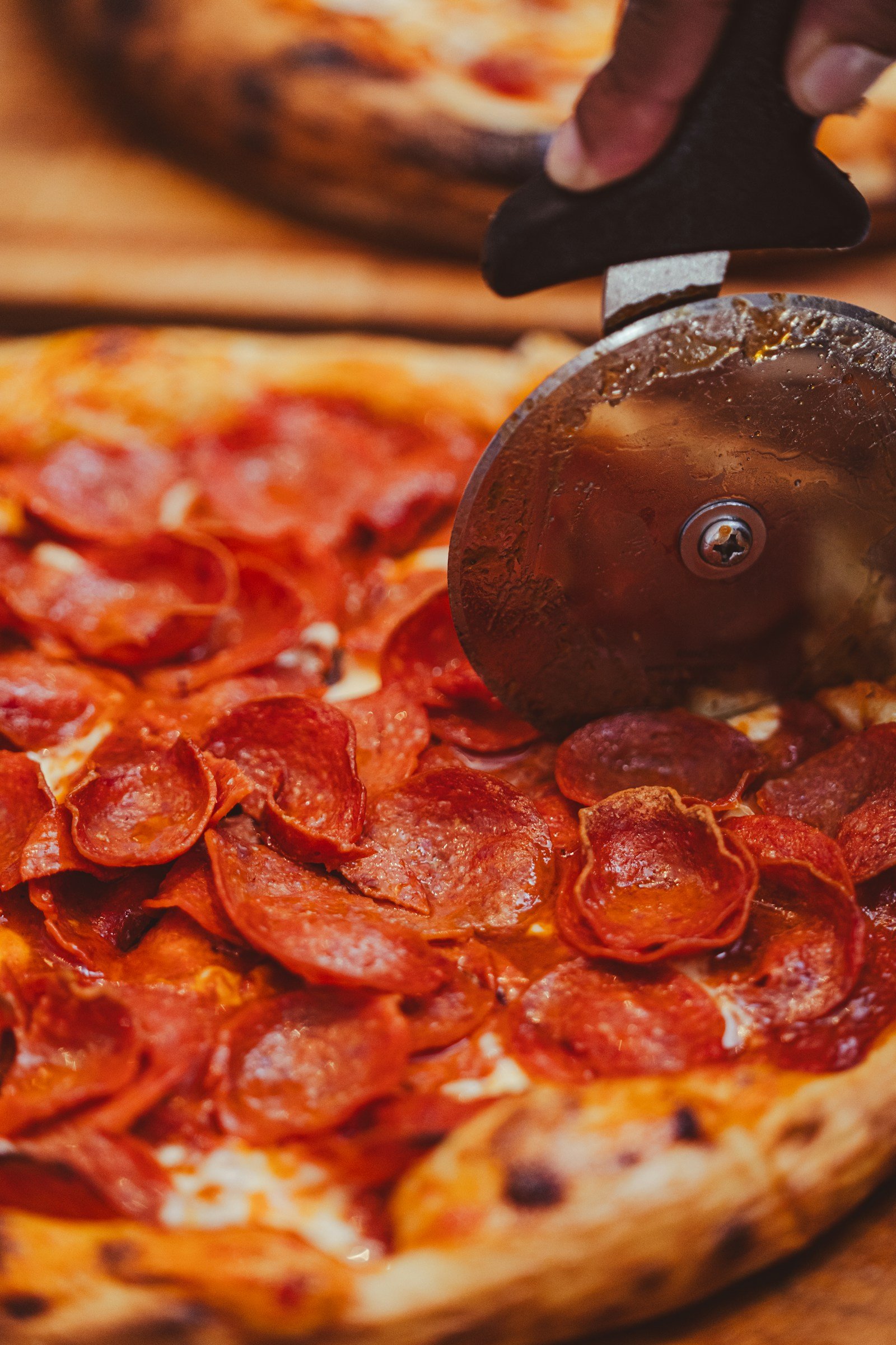A pepperoni pizza being cut with a pizza cutter